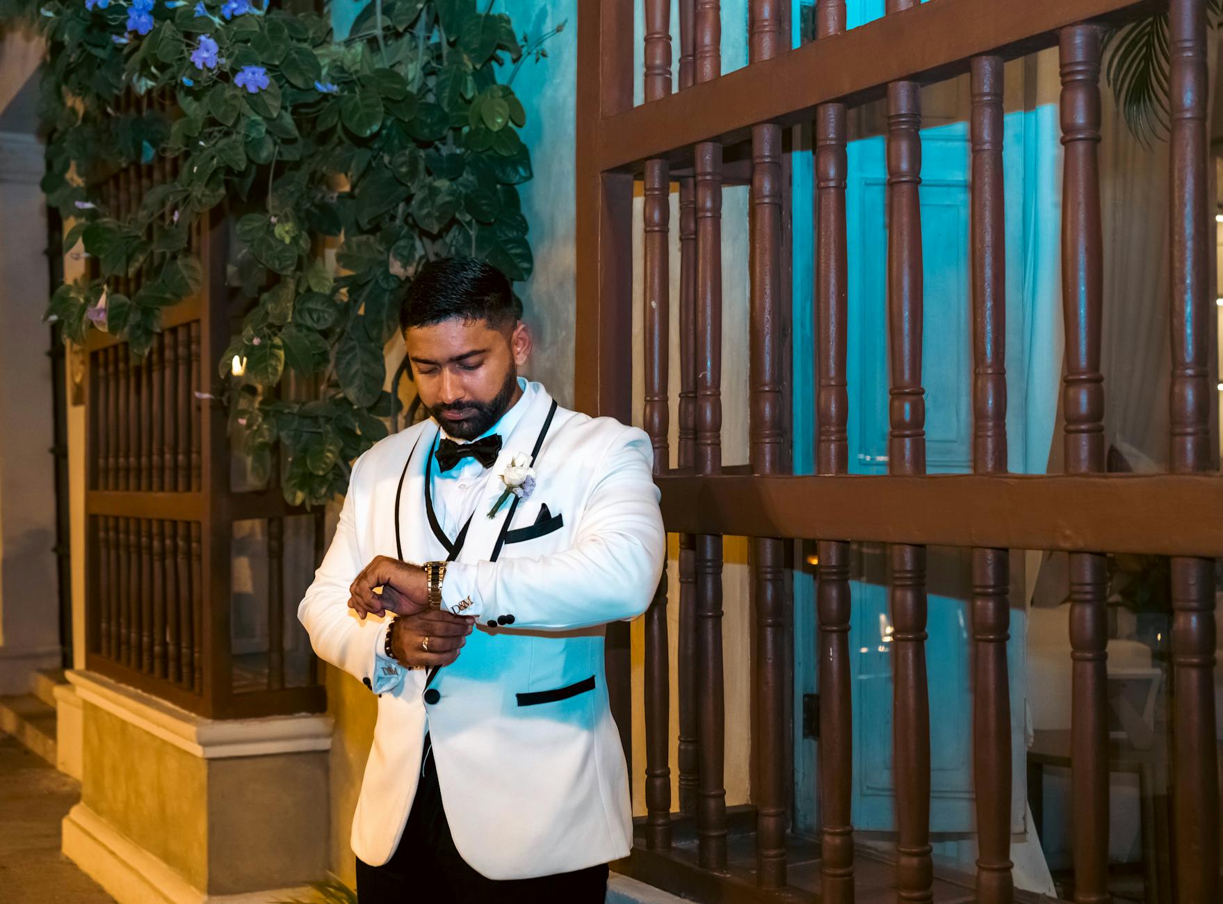 Mężczyzna w białym smokingu poprawia zegarek na wieczornym przyjęciu outdoors