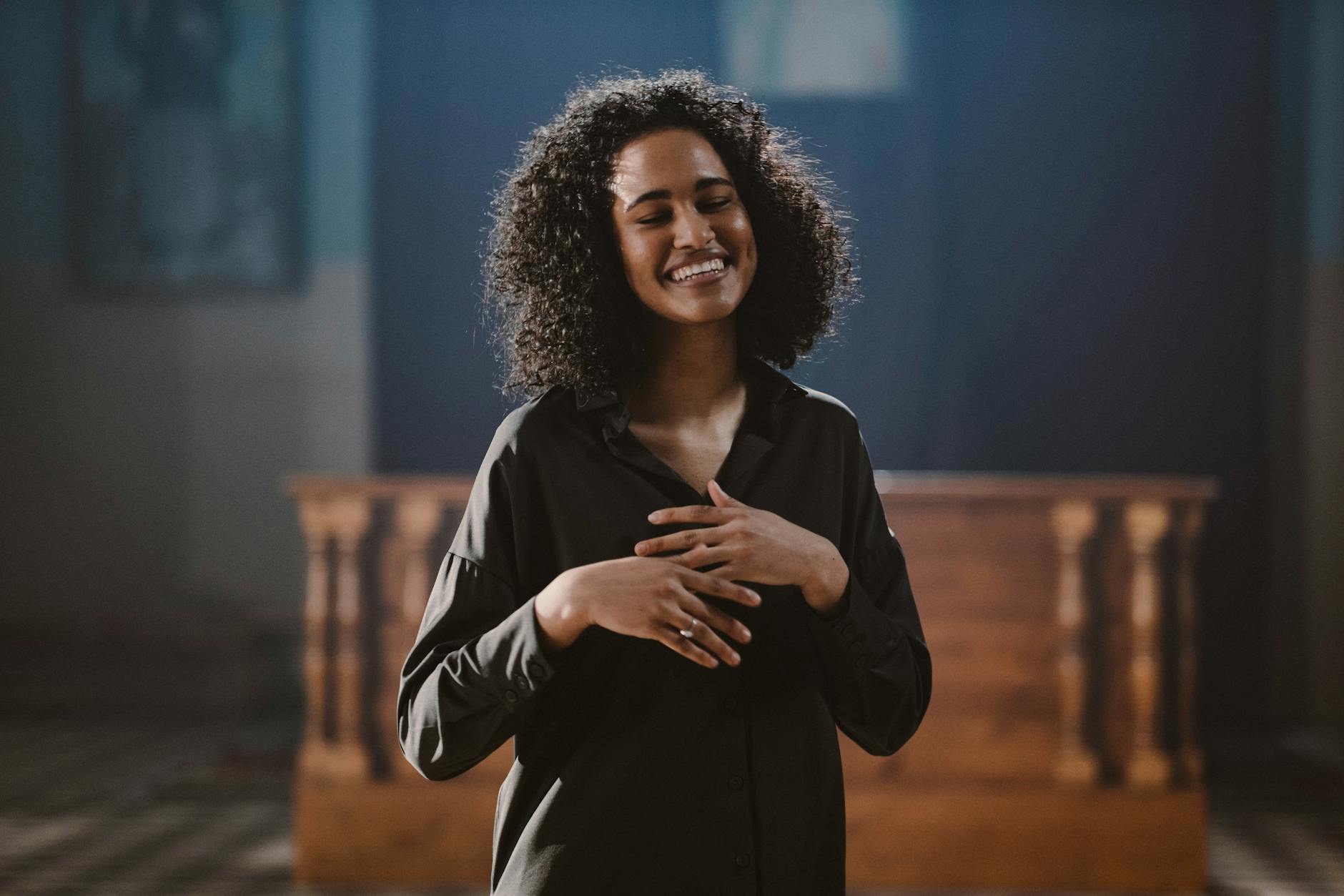 Młoda kobieta z kręconymi włosami śpiewa z zaangażowaniem w kościele