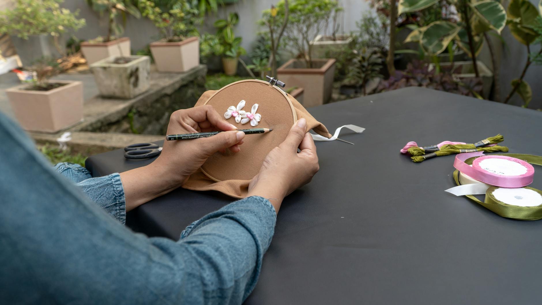 Dłonie haftujące na świeżym powietrzu kolorowymi wstążkami i włóczką