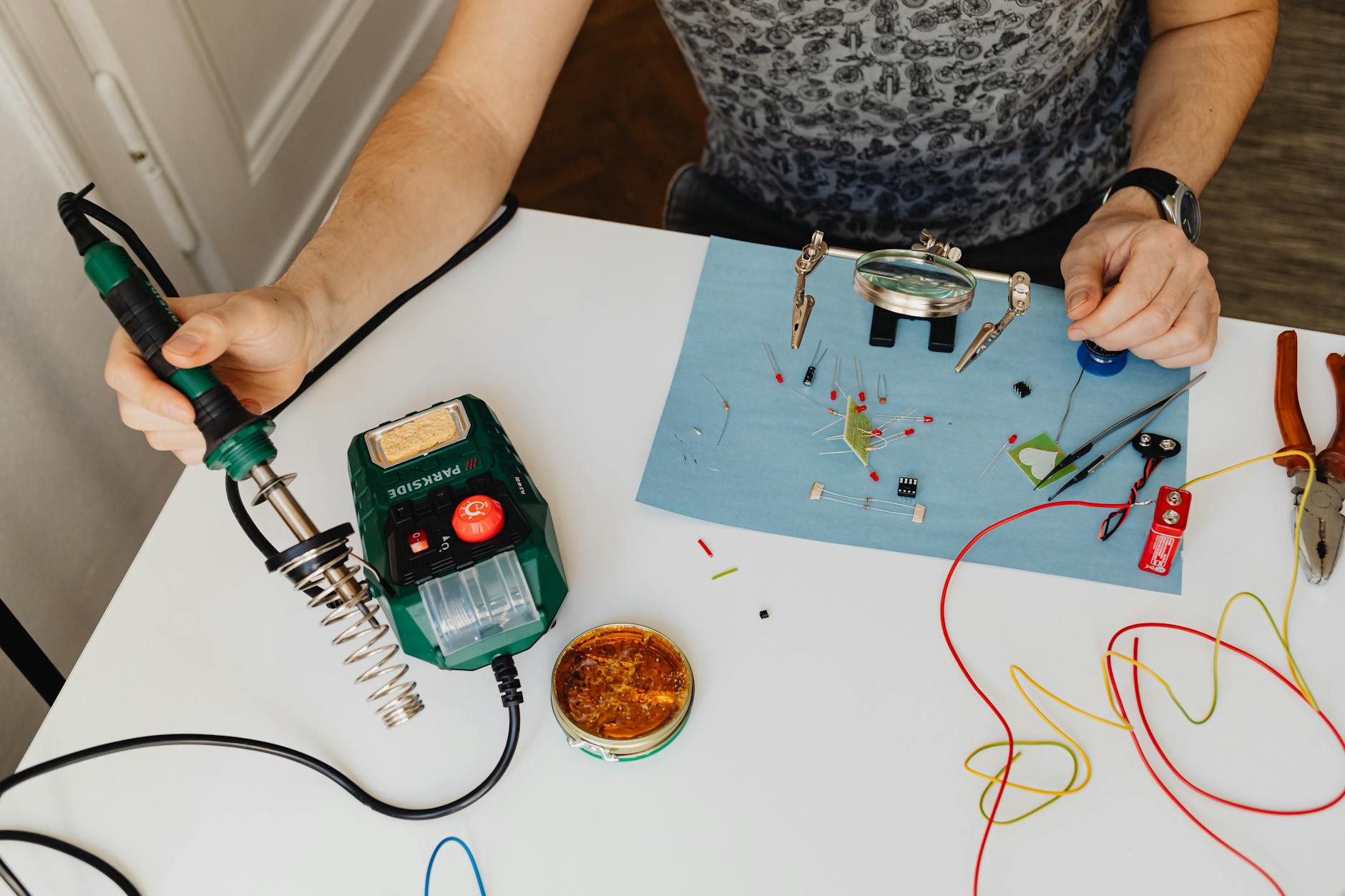Mężczyzna lutuje elementy elektroniczne na stole warsztatowym
