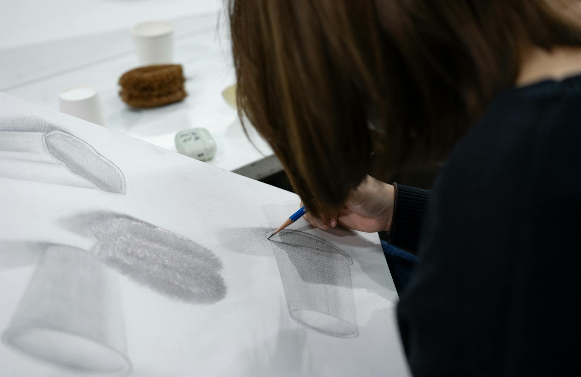 Uczeń plastyki szkicuje martwą naturę w sali lekcyjnej