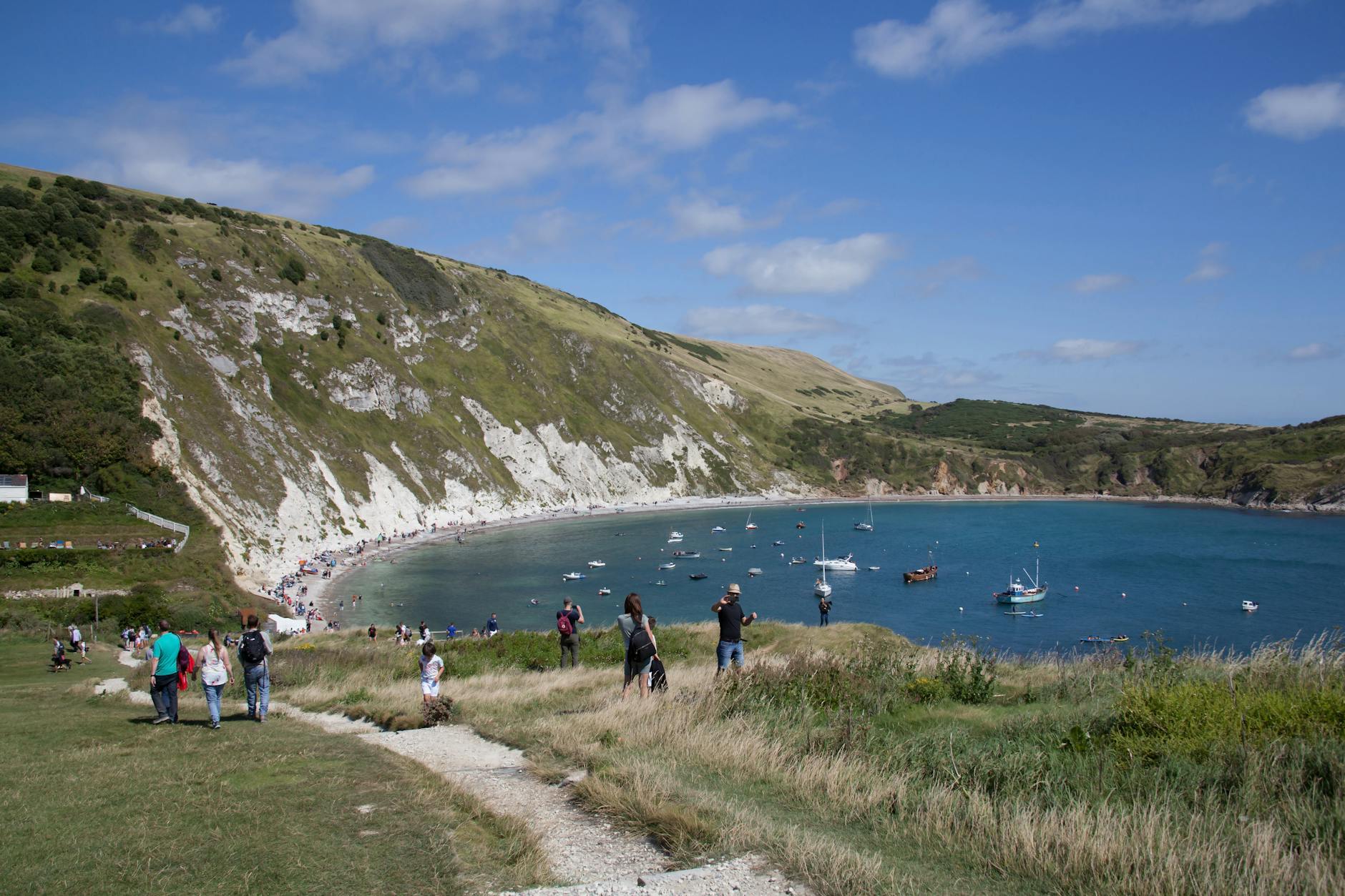 Zatoka Lulworth Cove w Anglii z turystami i małymi łódkami