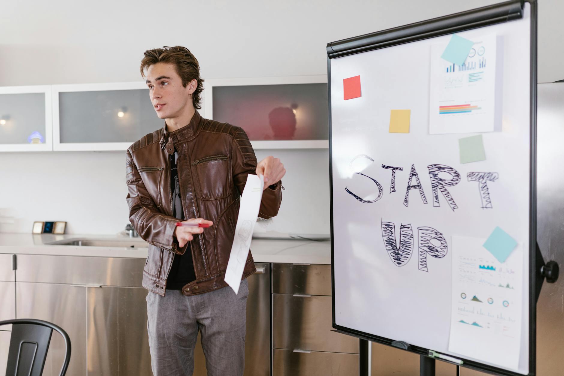 Młody przedsiębiorca prezentuje strategie startupu przy tablicy flipchart