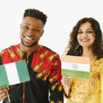 Patriotyzm dziś: jak dbać o wspólnotę bez wykluczania innych Nigeryjczyk i Induska w domu uśmiechają się, trzymając swoje flagi